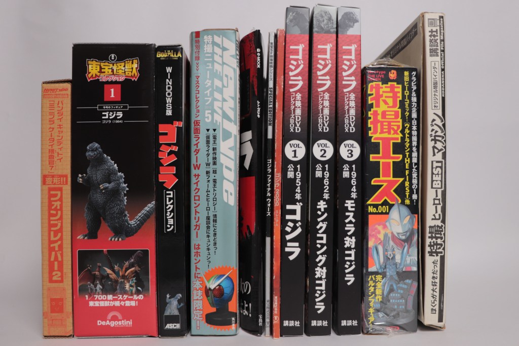 特撮本が並ぶ書棚、ゴジラやウルトラマンなどのタイトルが見える